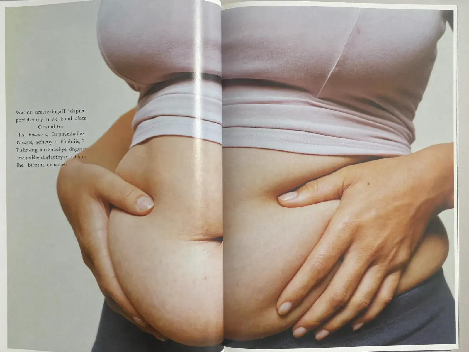 A woman holding her stomach against a pale studio background.