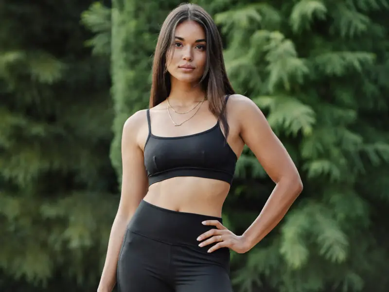 A young woman in activewear standing outdoors in soft morning light.