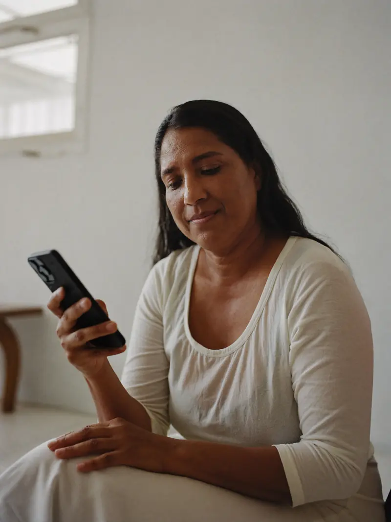 A woman reading her phone by a window, calm and absorbed.