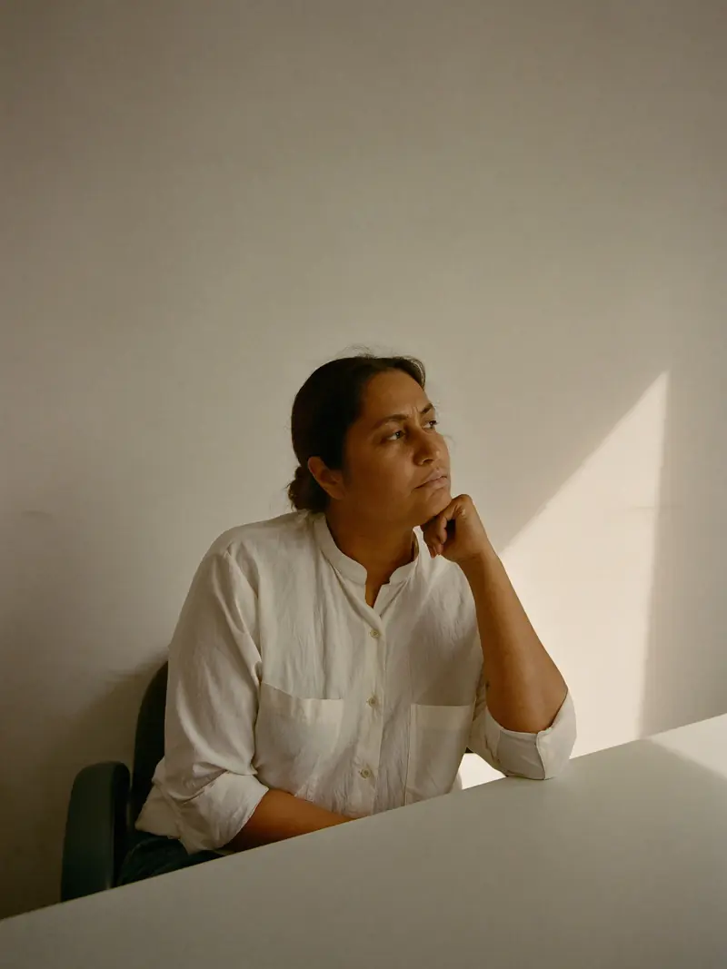 A woman pausing at her desk in late afternoon light.