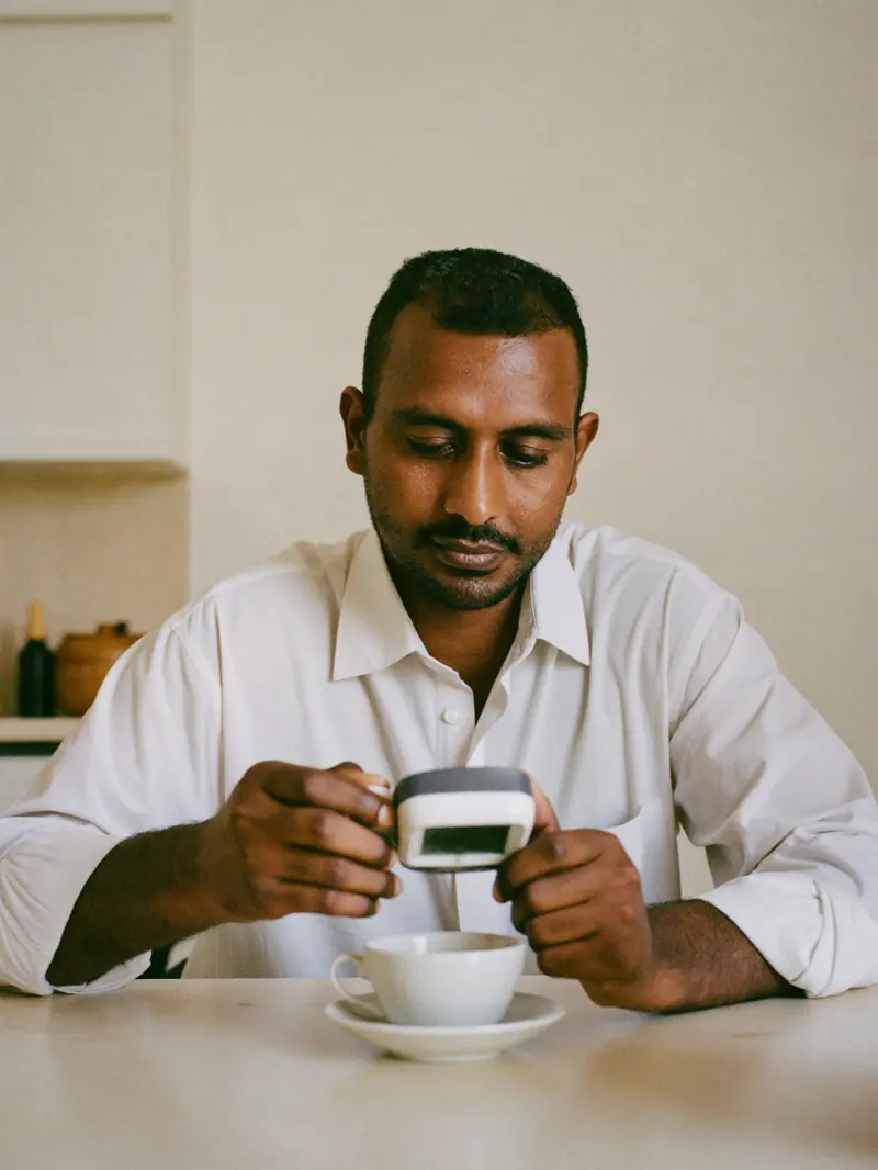 A man at his kitchen table in the morning, checking a small glucose meter.